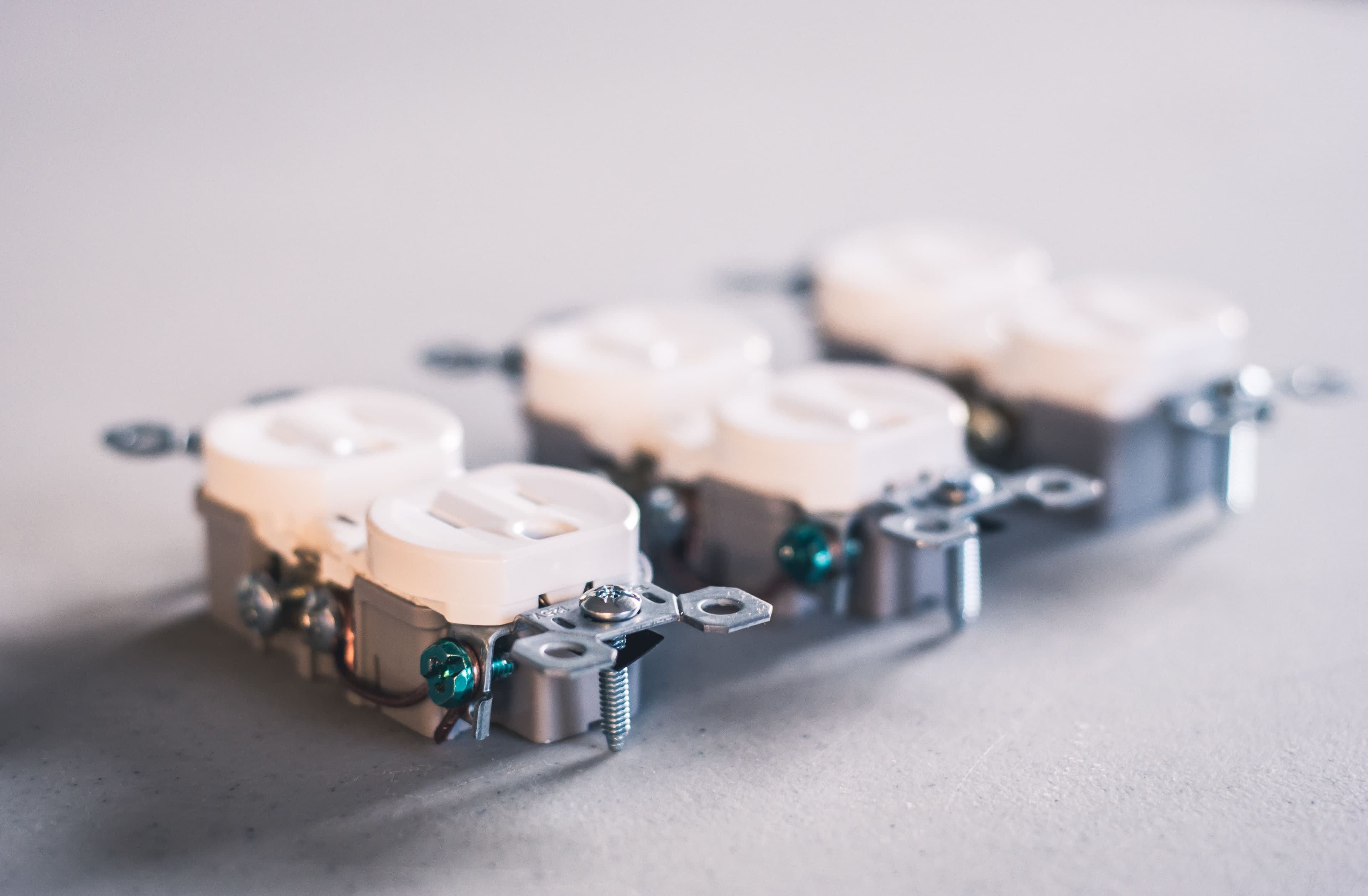 Three white electrical receptacles on a gray surface