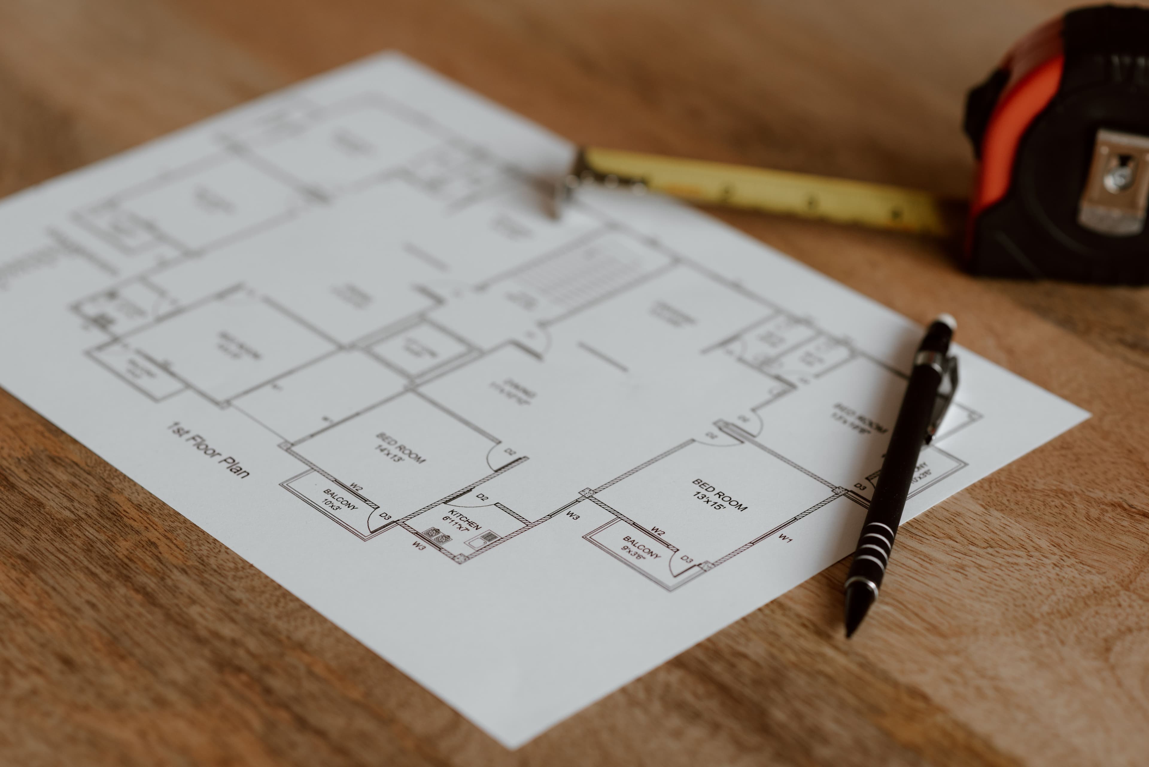 Floor plan on a wooden surface with a pen and tape measure