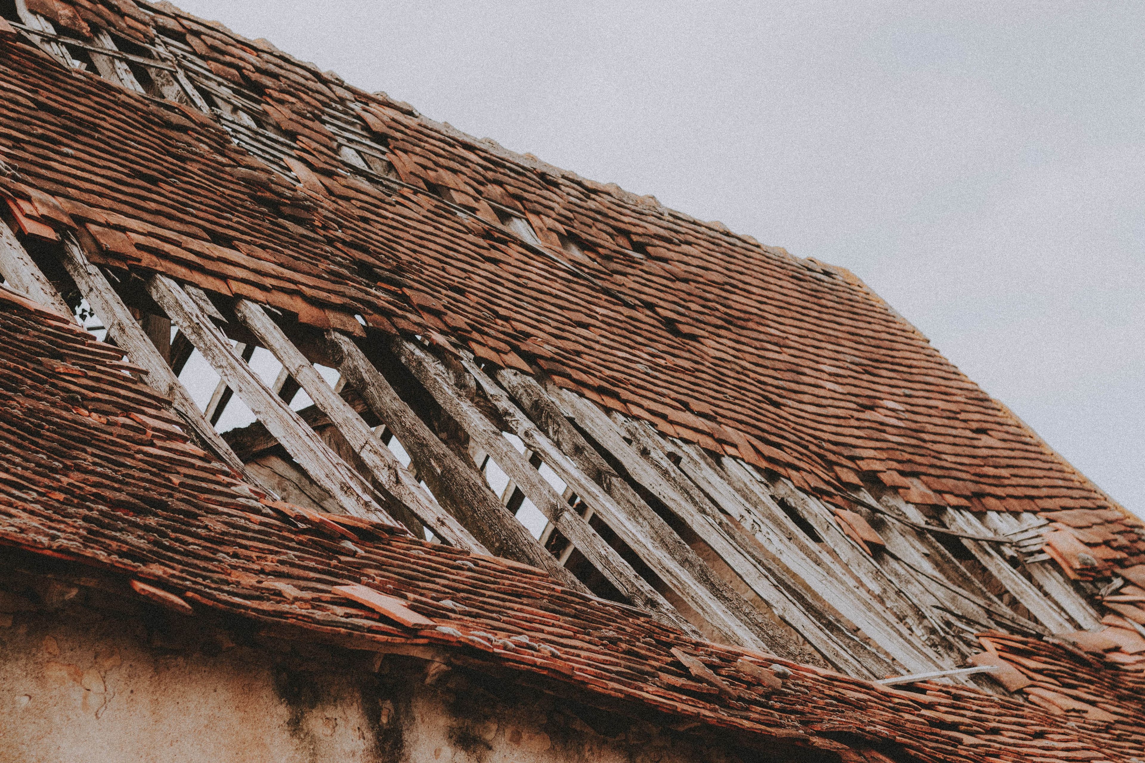 Weathered roof tiles with exposed wooden battens and missing sections